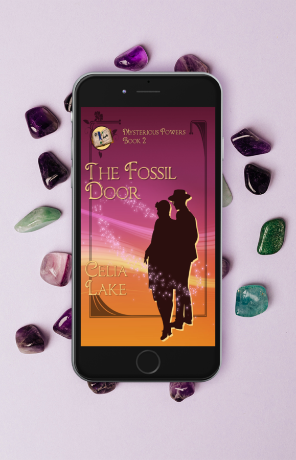 Cover of The Fossil Door displayed on a cell phone, lying on a scattering of tumbled stones in shades of purple and green.