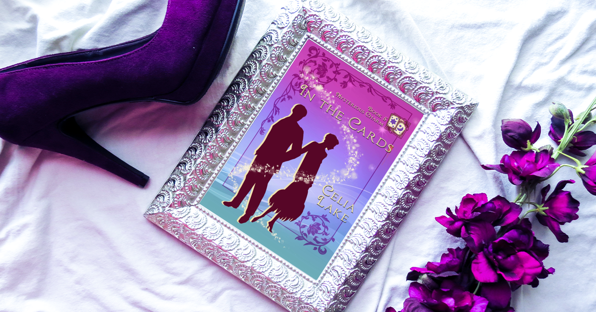 Cover of In The Cards displayed in a gleaming silver frame, with purple flowers on the right and a purple velvet high-heeled shoes.