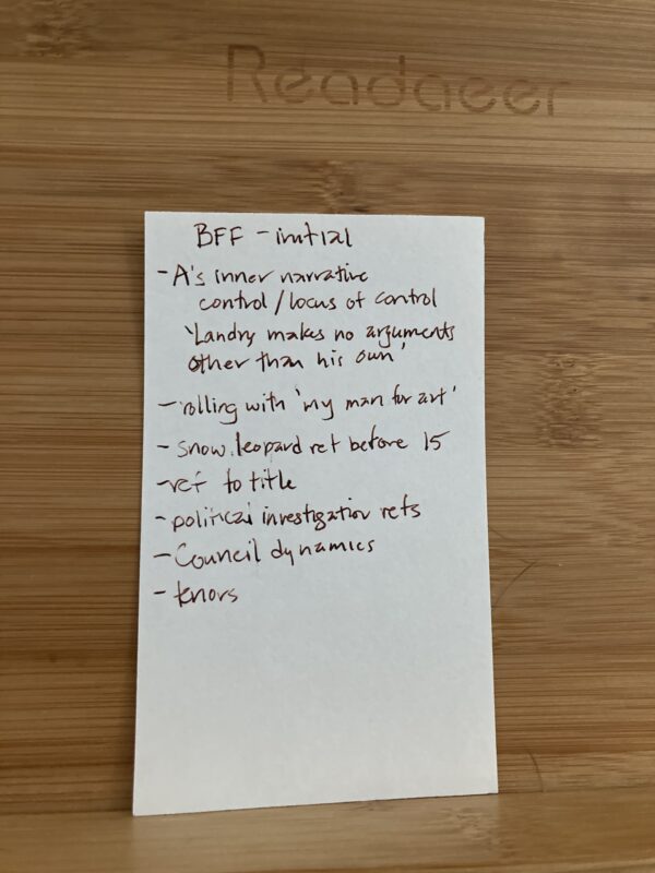 Index card with handwritten notes in copper ink, titled "BFF - initial" resting on a wooden reading stand. Full transcription in the following text.