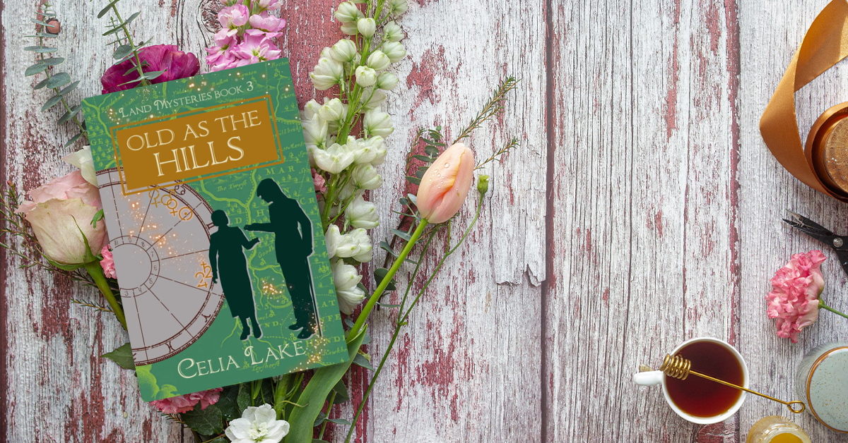 Old As The Hills sitting on a bouquet of flowers - rosses, sweetpeas, and others, on a whitewashed bench with honey, tea, and other summery things. The cover of Old As The Hills has a man with a can and a woman silhouetted on a green ground with a map. She holds out her hand, he is putting something into it, forming a doorway between them. An astrological chart behind them shows the symbols for Venus, the Sun, Jupiter, and Saturn highlighted behind a splash of glowing stars.