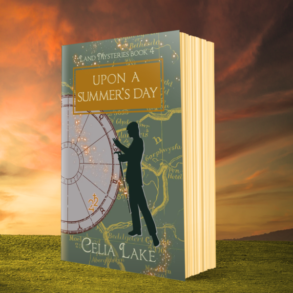 A copy of Upon A Summer's Day against a sunset, standing on grass. The cover of Upon A Summer's Day shows a man in a suit silhouetted over a map of northern Wales in a muted green. He is gesturing, holding his cane in one hand, a cap on his head. Behind him is an astrological chart, with Jupiter and Saturn highlighted in the sign of Taurus.
